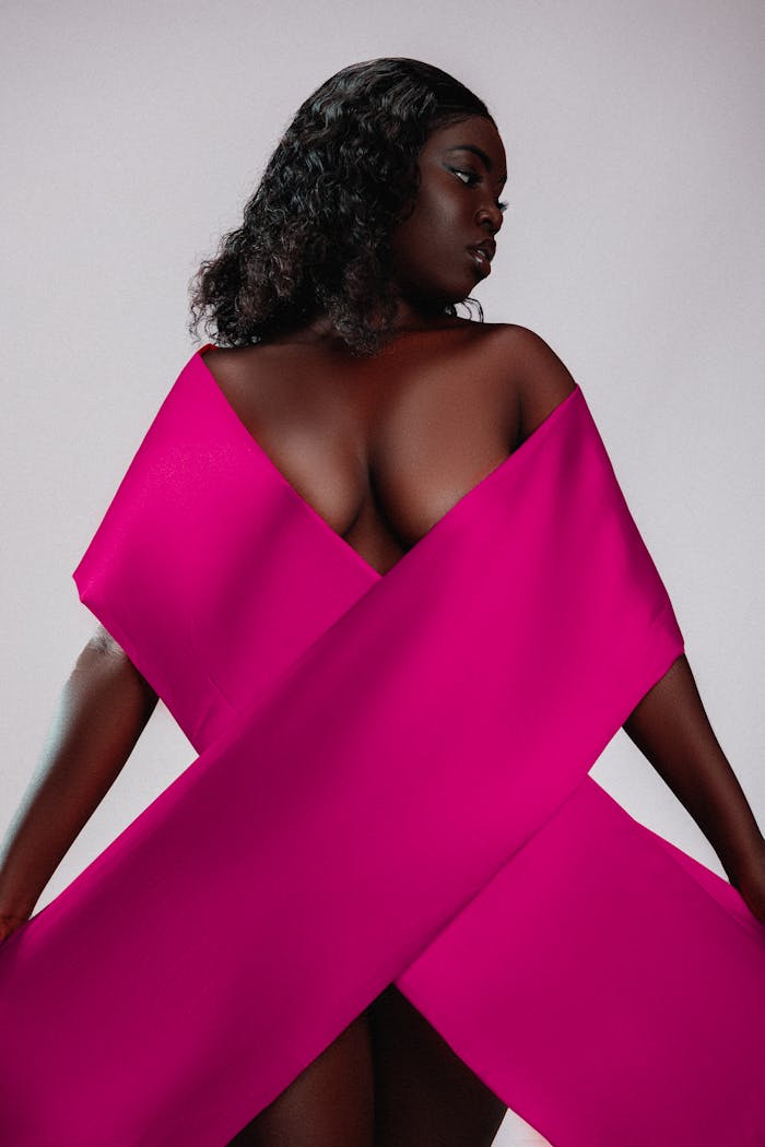 Striking studio portrait of a woman posing with a pink ribbon, symbolizing breast cancer awareness.